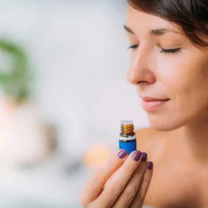 Een vrouw sluit haar ogen en ruikt aan een flesje etherische olie tijdens een leuke workshop aromatherapie in Antwerpen.