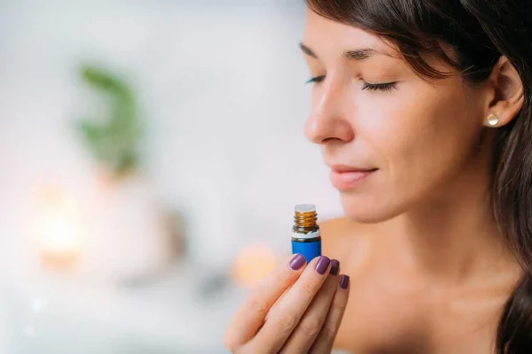 Een vrouw sluit haar ogen en ruikt aan een flesje etherische olie tijdens een leuke workshop aromatherapie in Antwerpen.
