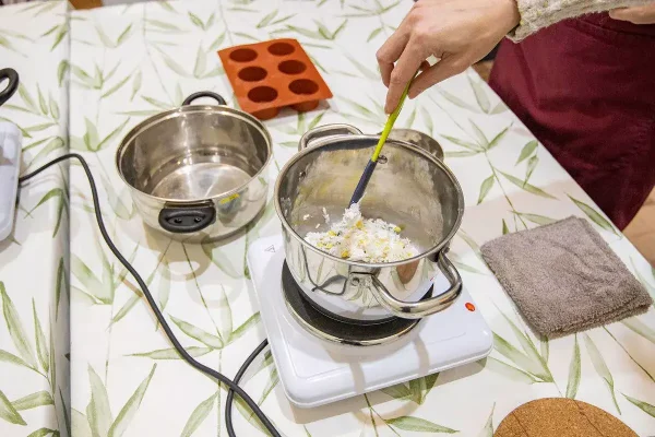 Een kookpot met verschillende ingrediënten om shampoobars te maken staat op het vuur.